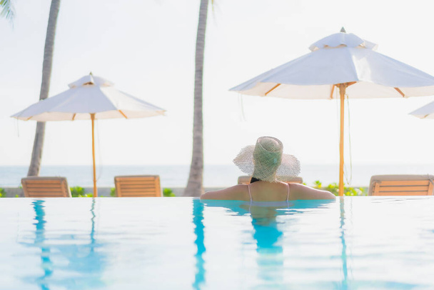 Retrato hermosa mujer asiática joven relajarse ocio alrededor de la piscina al aire libre con vista al mar playa océano en viajes de vacaciones - Foto, imagen