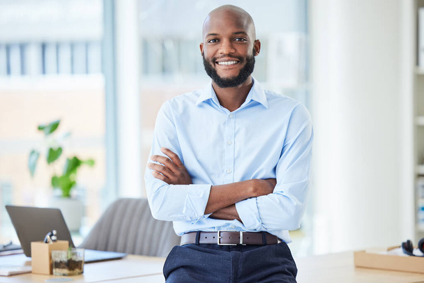 オフィスで腕を持って立っている自信のあるビジネスマンは,誇り高く,仕事で一人で幸せそうに見えました. 企業で働く笑顔で陽気でプロフェッショナルなアフリカの男性ボス. - 写真・画像