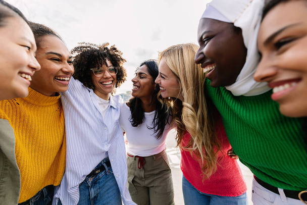 Hét boldog fiatal felnőtt nő különböző kultúrákból, akik együtt nevetnek a szabadban. Női barátság koncepció változatos csoport lányok barátok ölelés egymást szórakozás a város utcáin - Fotó, kép