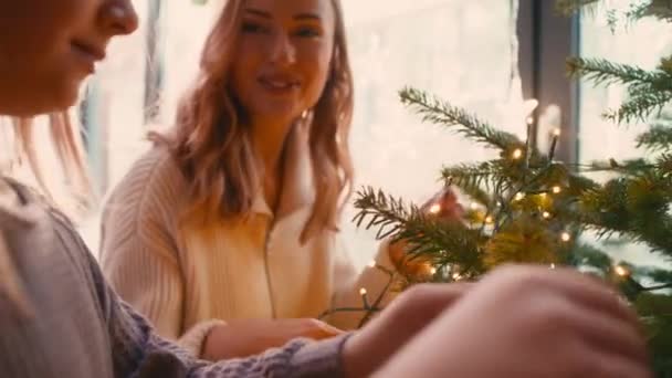 Λευκή γυναίκα και η κόρη της στολίζουν το χριστουγεννιάτικο δέντρο με φώτα. Πυροβολήθηκε με κόκκινη κάμερα ηλίου σε 8K.    - Πλάνα, βίντεο