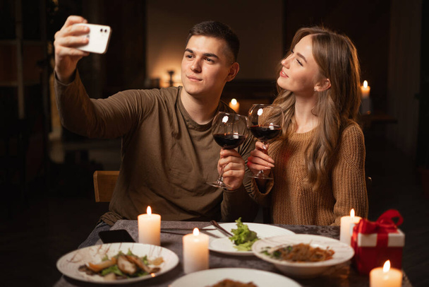 Молода пара закохана, приймаючи селфі під час вечері вдома або в ресторані, святкуючи день валентина, насолоджуючись часом, проведеним разом. Копіювати простір - Фото, зображення
