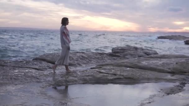 Vrouw in trui die bij zonsondergang over het strand loopt. Spanje, Alicante - Video