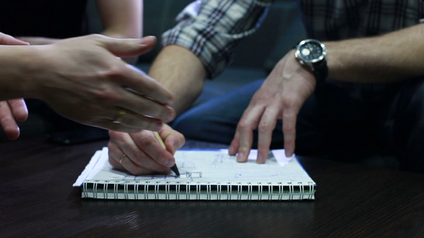 Progetto di disegno. Mani di giovani che disegnano una bozza con penna sul taccuino in ufficio durante l'incontro. Da vicino.
 - Filmati, video