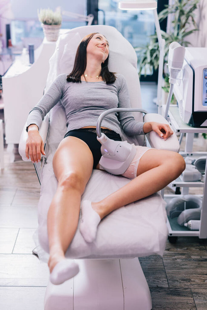 Cliente del salone di bellezza, una donna ottiene una procedura di criolipolisi sulla coscia per ridurre il grasso da un estetista. - Foto, immagini