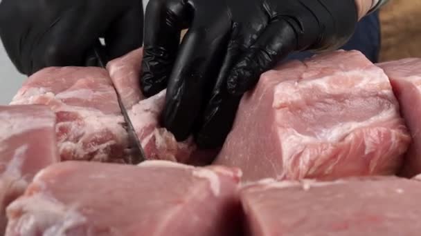 Teurastaja leikkaa liharuhon. Lähikuva veitsestä, joka leikkaa palan raakaa lihaa. Raaka liha lähikuva. - Materiaali, video
