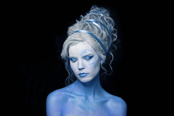 Retrato de belleza de moda de una joven modelo agradable con piel azul, maquillaje de escenario y peinado sobre fondo gris - Foto, imagen