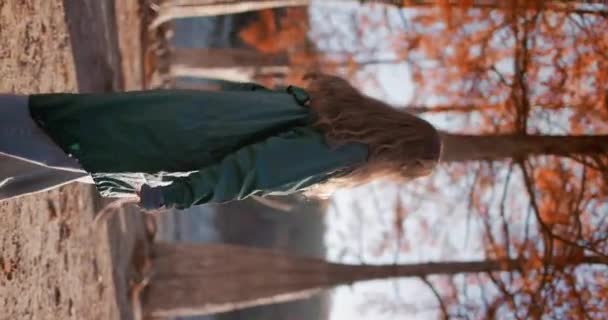Vonzó, boldog nő sétál az őszi parkban, és a kamerába néz. Gyönyörű lány a természetben naplementekor. Aktív életmód. Emberek az erdőben. - Felvétel, videó
