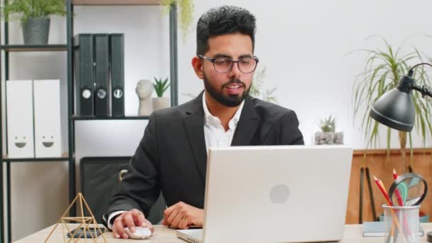 Πορτρέτο της Ινδίας γενειοφόρος επιχειρηματίας πρόσωπο ελεύθερος επαγγελματίας στο γραφείο στο σπίτι σύγχρονο χώρο εργασίας που εργάζονται σε φορητό υπολογιστή. Διευθυντής freelancer Arabian άνθρωπος εργάζεται για notebook στείλετε μηνύματα κάνει online αγορές - Πλάνα, βίντεο