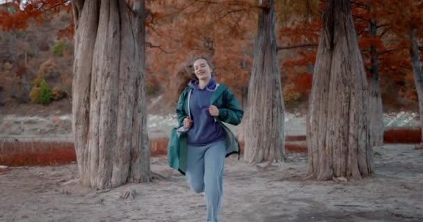 Atractiva mujer corriendo por el parque y mirando a la cámara. Fantasía de la gente en el parque en otoño. Estilo de vida activo. Personas en el bosque. - Imágenes, Vídeo
