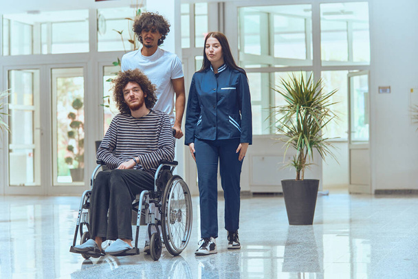 Een arts en een verpleegkundige werken samen om een patiënt in een rolstoel door een modern ziekenhuis te vervoeren, als voorbeeld van teamwerk en efficiënt zorgbeheer..  - Foto, afbeelding