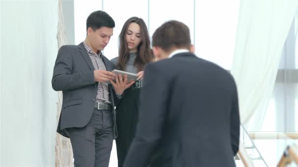 Een groep jonge zakenlieden analyseerde en discussieerden. Op de voorgrond een jonge man met een notebook. Op de achtergrond een jong stel zakenlieden. - Video