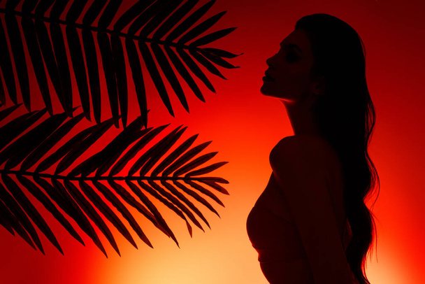 Foto della signora in posa sotto le foglie di palma godere di sera crepuscolo sulla spiaggia dell'oceano su sfondo rosso giallo. - Foto, immagini