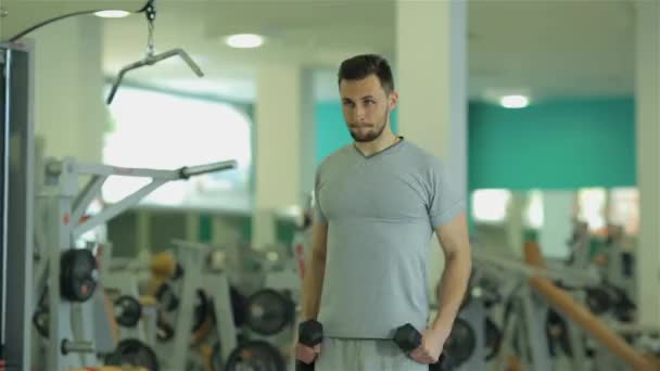 Mladý muž dělá cvičení s činkami pro biceps a triceps - Záběry, video
