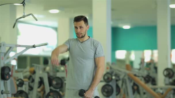 Młody człowiek robi 2 ćwiczenia z hantlami na triceps - Materiał filmowy, wideo
