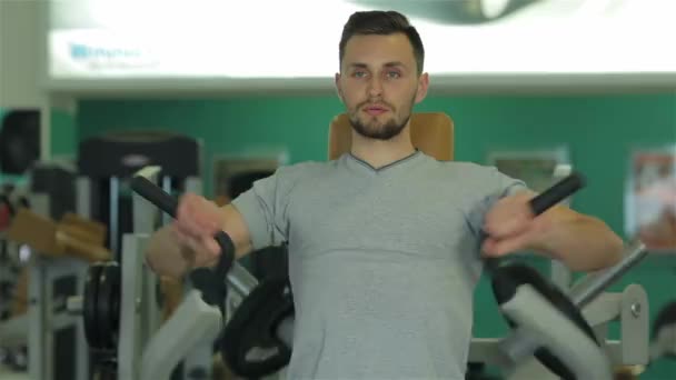 Kijken naar de camera jonge man doen oefening voor de spieren van de borst. Schuif in het frame van links naar rechts. - Video