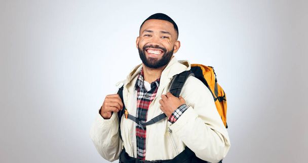 Man, portrait and hiking in studio with backpack and smile from travel and freedom with adventure. Camping, fitness and grey background and walking with trekking camper gear for vacation and holiday. - Foto, Imagem