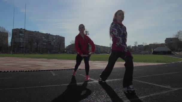 As meninas passam exercícios de treinamento antes da corrida. músculos da perna exercícios de aquecimento
 - Filmagem, Vídeo