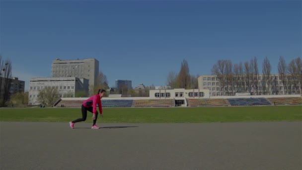 Young girl doing a race at the stadium. Become a rack to start, starts running. Runs from left to right in the frame - Footage, Video