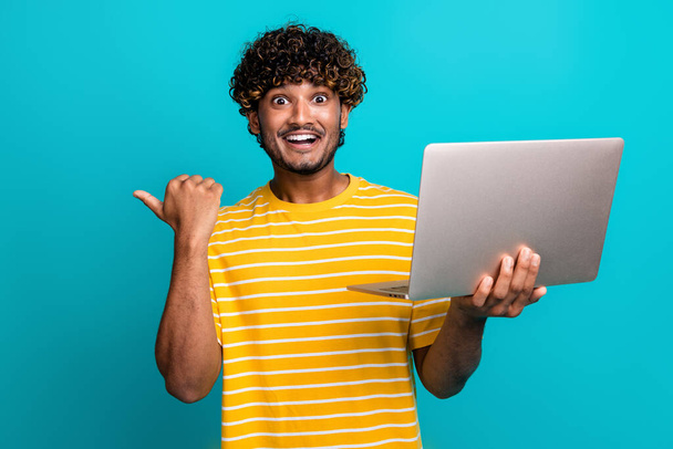 Portrait of impressed american man hold wireless laptop direct finger empty space ad isolated on turquoise color background. - Фото, зображення