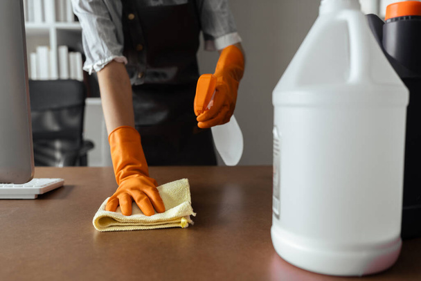 Γυναικείο καθάρισμα και σκούπισμα τραπεζιού με ύφασμα από μικροΐνες στο γραφείο. - Φωτογραφία, εικόνα