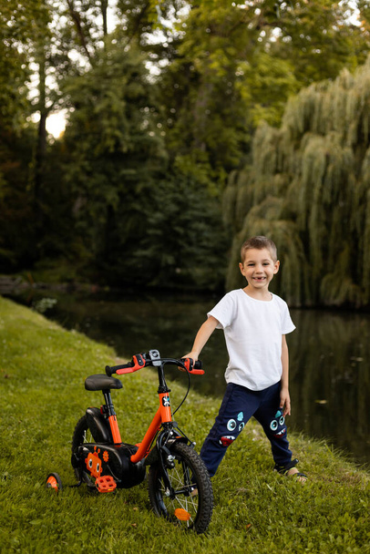 男の子が湖の近くの公園で自転車に乗っている. スクールボーイズ休暇。 高品質の写真 - 写真・画像