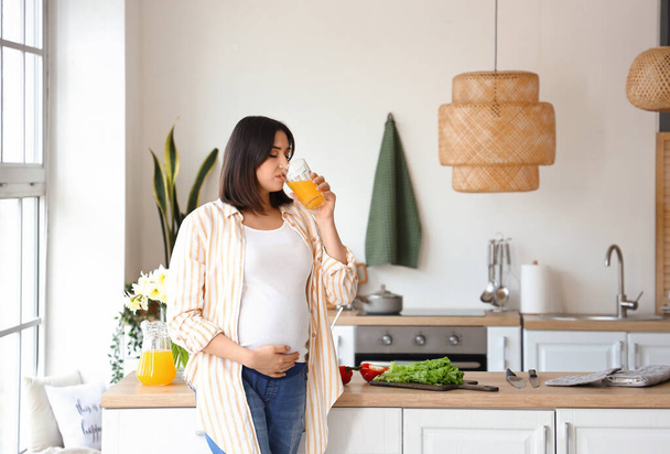 Nuori raskaana oleva nainen juo mehua keittiössä - Valokuva, kuva