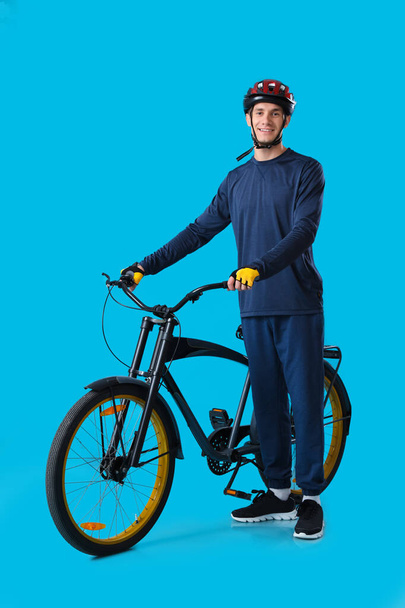 Mavi arka planda bisikleti olan genç adam. - Fotoğraf, Görsel