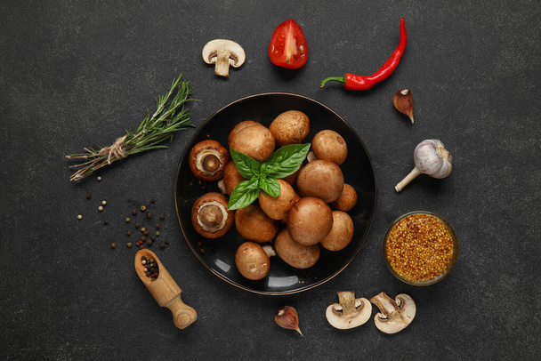 Prato com cogumelos frescos e especiarias diferentes sobre fundo preto - Foto, Imagem
