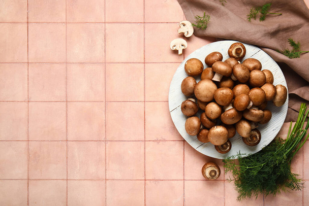Teller mit frischen Pilzen und Dill auf rosa Fliesen Hintergrund - Foto, Bild
