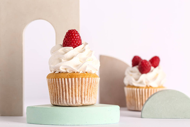 Decorative stand with tasty raspberry cupcakes on grey background - Photo, Image