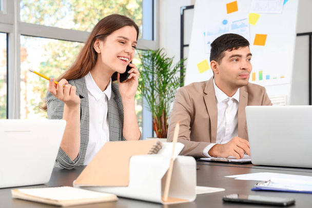 Jeune femme d'affaires parlant par téléphone portable lors d'une réunion au bureau - Photo, image