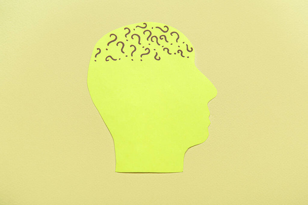 Papier menselijk hoofd met vraagtekens op groene achtergrond. Dag van de geestelijke gezondheid - Foto, afbeelding