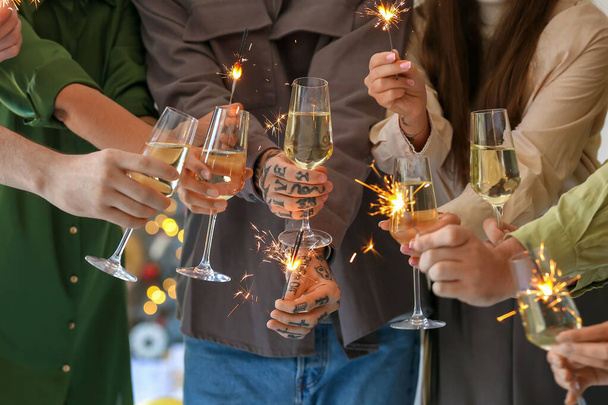 Group of friends with champagne and sparklers celebrating New Year at home party, closeup - Photo, Image
