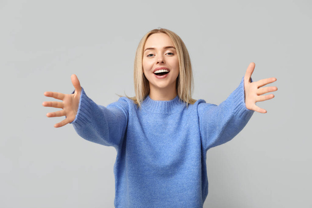 Young woman opening arms for hug on grey background - Photo, Image