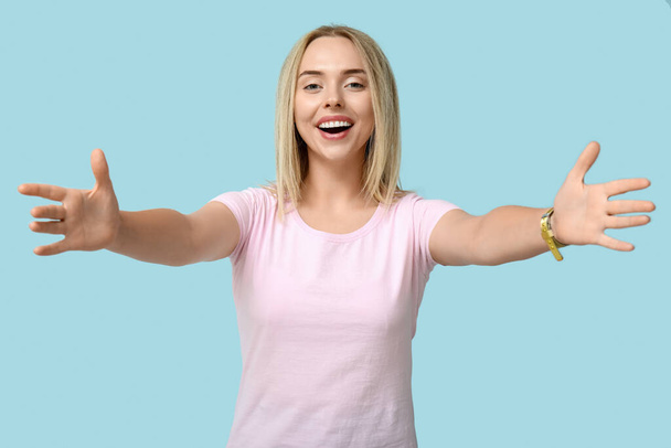 Young woman opening arms for hug on blue background - Photo, Image