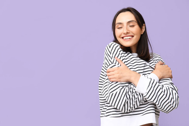 Молодая женщина обнимает себя на фоне сирени - Фото, изображение