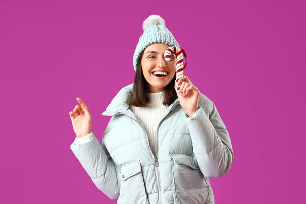 fiatal nő téli ruhák játék cukornád lila háttér - Fotó, kép