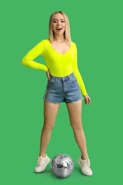 Gyönyörű fiatal nő disco labda zöld háttér - Fotó, kép