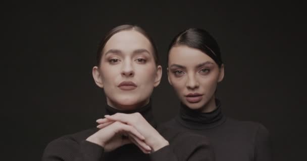 Δύο νεαρές κομψές γυναίκες με καλό μακιγιάζ σε μαύρο φόντο. Αργή κίνηση, Studio shot. - Πλάνα, βίντεο