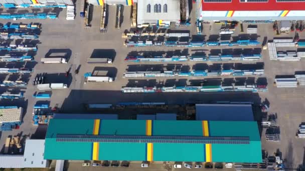Puoliperävaunulliset kuorma-autot seisovat logistiikkapuiston parkkipaikalla lastauskeskuksineen ja odottavat lastaus- ja purkutavaroita varaston ramppien luona auringonlaskun aikaan. Antenninäköala - Materiaali, video