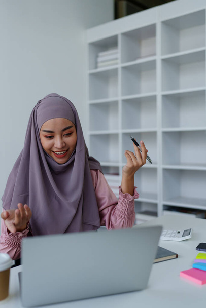 Muslimische Mitarbeiterinnen konferieren während der Arbeit per Computer - Foto, Bild