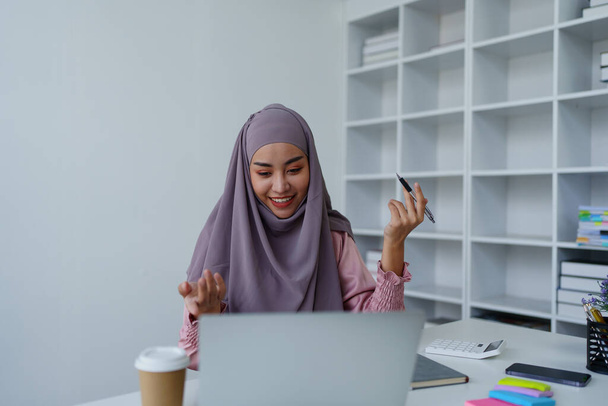 Moslim vrouwelijke werknemer Conferencing via computer tijdens het werk - Foto, afbeelding
