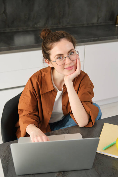 Foto vertical de mulher trabalhando em casa, empresária usando laptop, navegando nas mídias sociais no computador, usando óculos. - Foto, Imagem