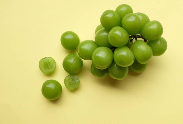 Bunch of fresh Sweet Green Shine Muscat (Vitis vinifera) grape isolated on yellow backdrop.green grapes. Japanese grapes.Grapes green taste sweet growing natural. - Photo, Image