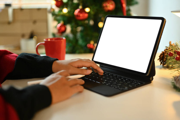 Vista de cerca de las manos de la mujer escribiendo en el teclado inalámbrico de la tableta digital que trabaja en casa durante las vacaciones de invierno. - Foto, imagen