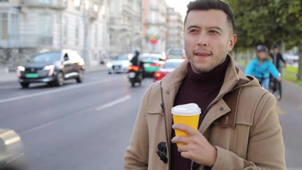 primo piano ritratto di bel giovane uomo con tazza di carta di caffè sulla strada della città - Filmati, video