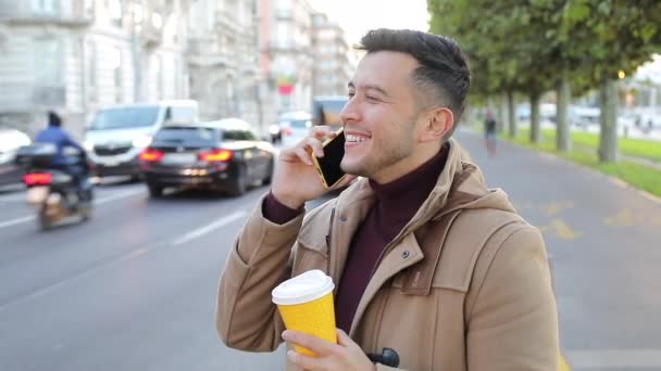close-up portretbeelden van knappe jongeman met smartphone en koffie op straat - Video