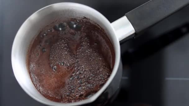 芳香のあるコーヒーはタークで沸騰し、つばに泡立ちます。朝の朝食やコーヒーブレイクのドリンク。自宅でカフェやキッチンで熱い飲み物を準備する伝統的な方法。閉じろ!. - 映像、動画