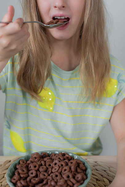 Küçük sarışın kız çikolatalı gevrek yiyor.  - Fotoğraf, Görsel
