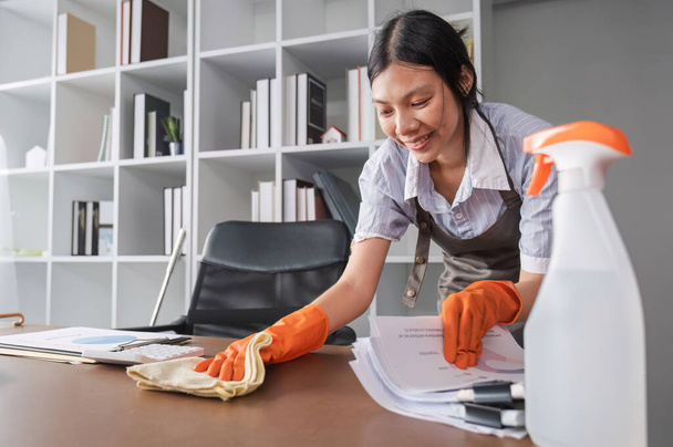 La jeune femme utilise une lingette nettoyante pour désinfecter l'ordinateur et l'équipement sur la table de bureau. Nettoyeur ou femme de ménage nettoie le bureau. - Photo, image